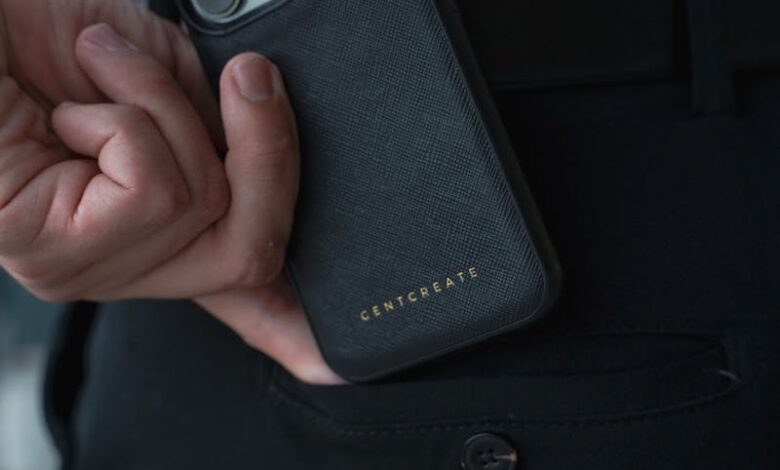 Close-up of a man holding a smartphone with a luxury case indoors.