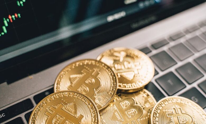 Close-up of gold Bitcoin coins on a laptop keyboard with a stock chart, symbolizing cryptocurrency market analysis.