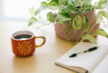 black retractable pen on opened book beside red and white go get'em-printed coffee cup