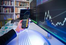 A man holding a remote control in front of a computer