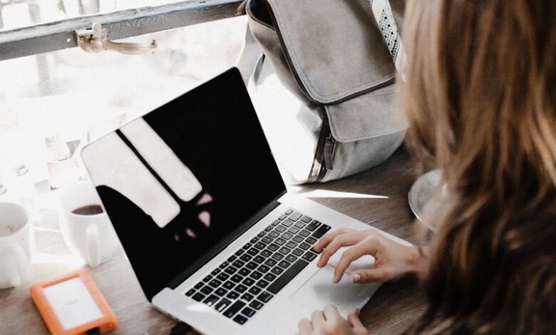 girl wearing grey long-sleeved shirt using MacBook Pro on brown wooden table